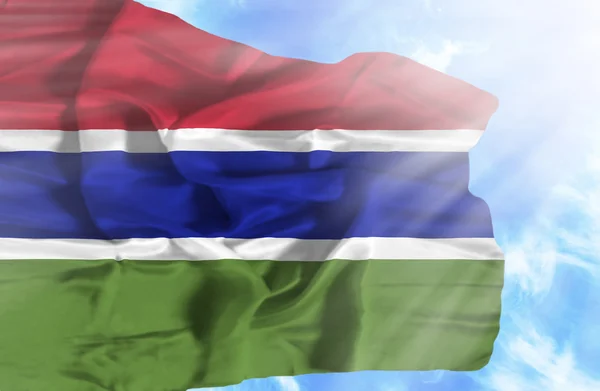 Gambie agitant drapeau contre ciel bleu avec des rayons de soleil — Photo