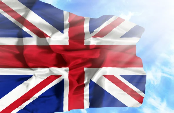 Grã-Bretanha agitando bandeira contra o céu azul com raios de sol — Fotografia de Stock