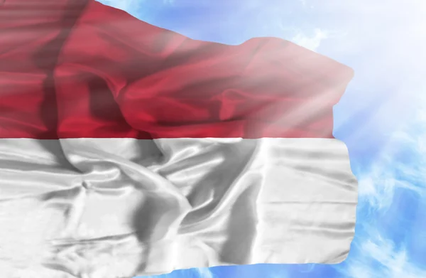 Indonesien schwenkt Flagge gegen blauen Himmel mit Sonnenstrahlen — Stockfoto