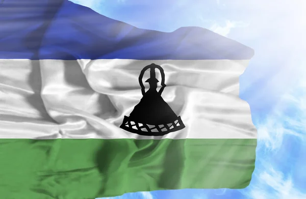 Lesotho viftande flagga mot blå himmel med solstrålar — Stockfoto