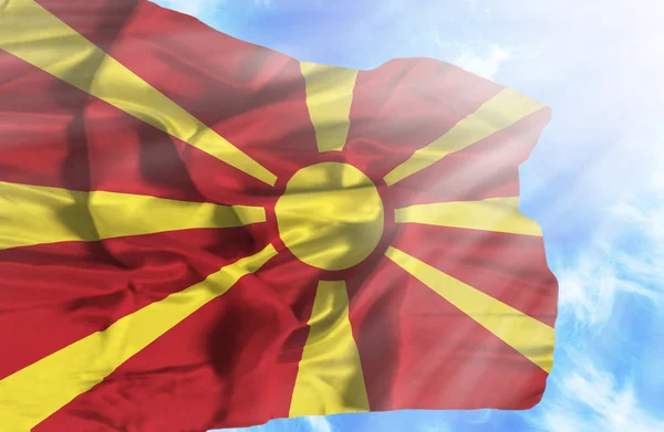 Macedonia ondeando bandera contra el cielo azul con rayos de sol — Foto de Stock