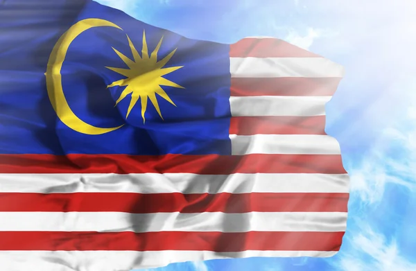 Malaysia schwenkt Flagge gegen blauen Himmel mit Sonnenstrahlen — Stockfoto