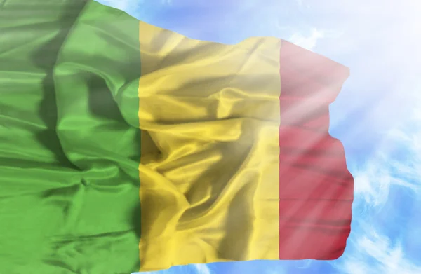 Drapeau du Mali agitant contre le ciel bleu avec des rayons de soleil — Photo