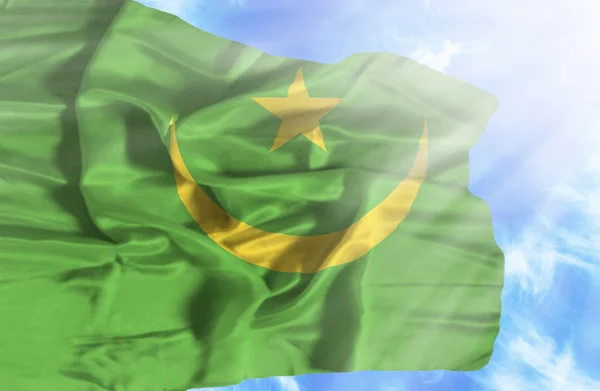 Mauritania ondeando bandera contra el cielo azul con rayos de sol —  Fotos de Stock