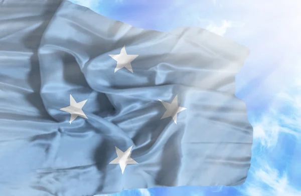 Micronesia, federale staten zwaaien vlag tegen blauwe hemel met zonnestralen — Stockfoto