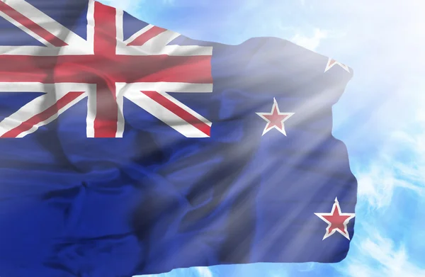 New Zealand waving flag against blue sky with sunrays — Stock Photo, Image