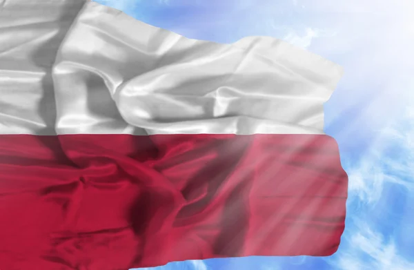 Poland waving flag against blue sky with sunrays — Stock Photo, Image