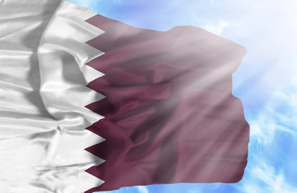 Qatar zwaaien vlag tegen blauwe hemel met zonnestralen — Stockfoto