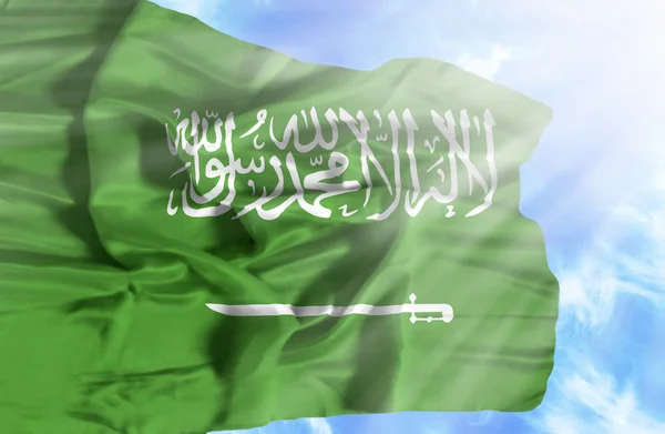 Arabia Saudita ondeando bandera contra el cielo azul con rayos de sol — Foto de Stock