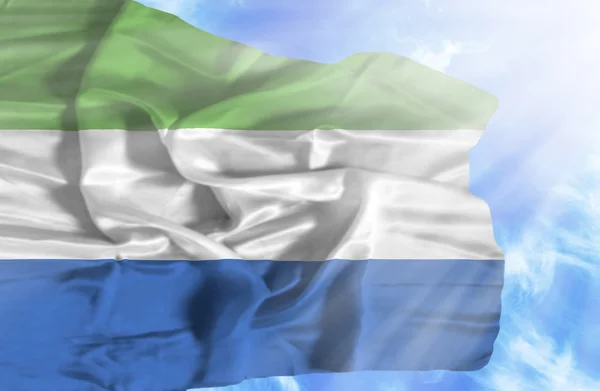 Sierra leone zwaaien vlag tegen blauwe hemel met zonnestralen — Stockfoto