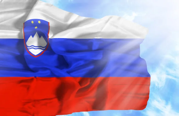 Slovenië zwaaien vlag tegen blauwe hemel met zonnestralen — Stockfoto