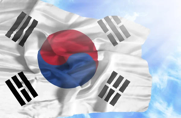 Corée du Sud agitant drapeau contre ciel bleu avec des rayons de soleil — Photo