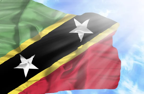 Saint-Kitts-et-Nevis agitant le drapeau contre le ciel bleu avec des rayons de soleil — Photo