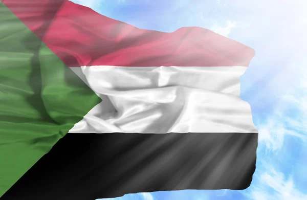 Sudan sventola bandiera contro il cielo blu con i raggi del sole — Foto Stock