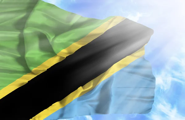 Tanzania viftande flagga mot blå himmel med solstrålar — Stockfoto