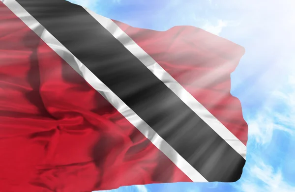 Trinidad und Tobago schwenken Flagge gegen blauen Himmel mit Sonnenstrahlen — Stockfoto