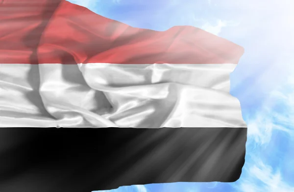 Yemen waving flag against blue sky with sunrays — Stock Photo, Image