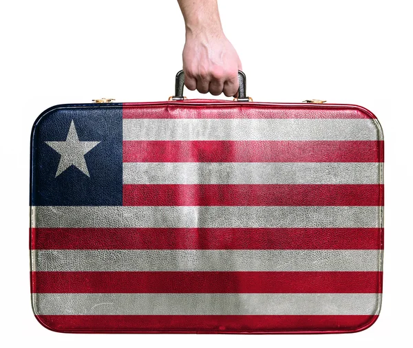 Turist hånd holder vintage læder rejsetaske med flag Lib - Stock-foto