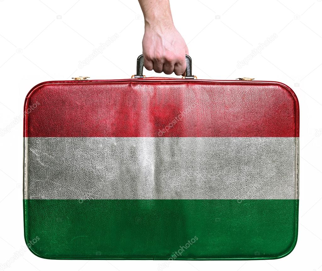 Tourist hand holding vintage leather travel bag with flag of Hun