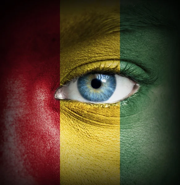 Menschengesicht mit Flagge von Guinea bemalt — Stockfoto