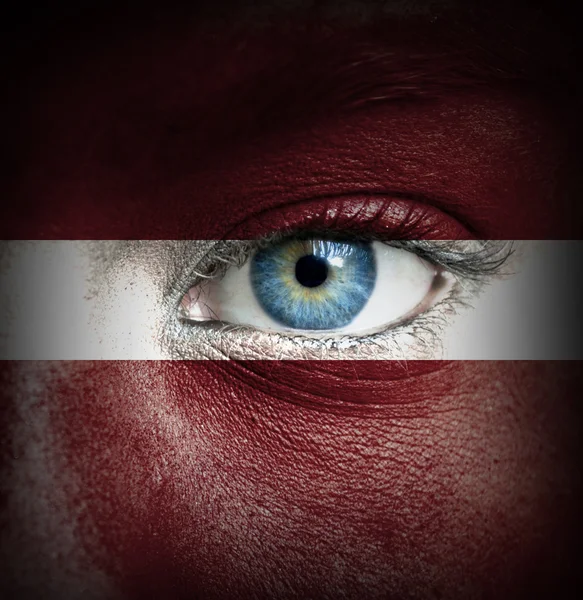 Human face painted with flag of Latvia — Stock Photo, Image