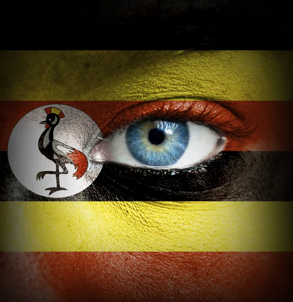 Human face painted with flag of Uganda — Stock Photo, Image