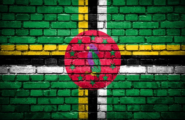 Ziegelsteinmauer mit bemalter Dominica-Fahne — Stockfoto