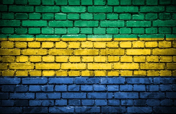 Cihlová zeď s malovanými vlajka Gabonu — Stock fotografie