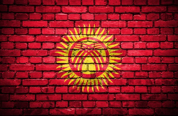 Ziegelsteinmauer mit bemalter Fahne von Kyrgyzstan — Stockfoto