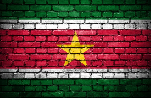 Parede de tijolo com bandeira pintada de Suriname — Fotografia de Stock