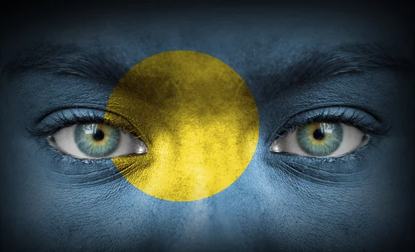 Human face painted with flag of Palau — Stock Photo, Image