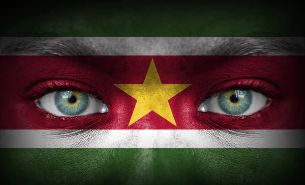 Ludzka twarz malowane z flaga Surinamu — Zdjęcie stockowe