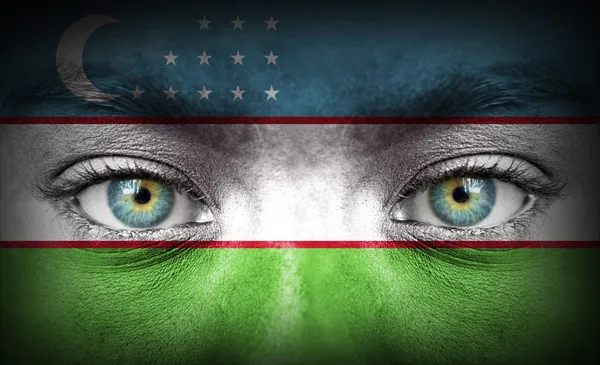 Human face painted with flag of Uzbekistan — Stock Photo, Image