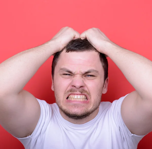 Portrait of angry man screaming and pulling hair against red bac — Stock Photo, Image