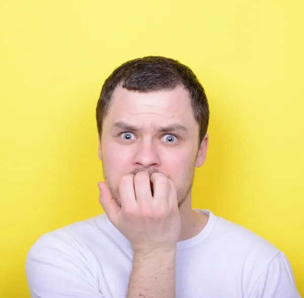 Porträtt av man bita naglar mot gul bakgrund — Stockfoto