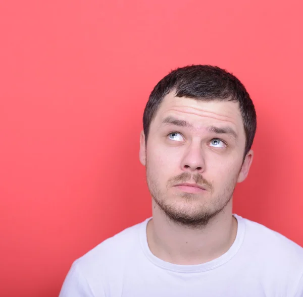 Portrait of man thinking and looking up against red background — Stock Photo, Image