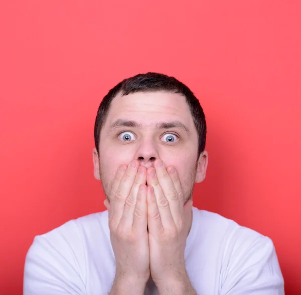 Portrait of man with hands covering mouth against red background — Stock Photo, Image