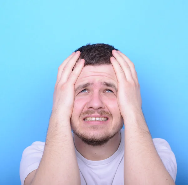 Portrait of sad man looking up against blue background — Stock Photo, Image