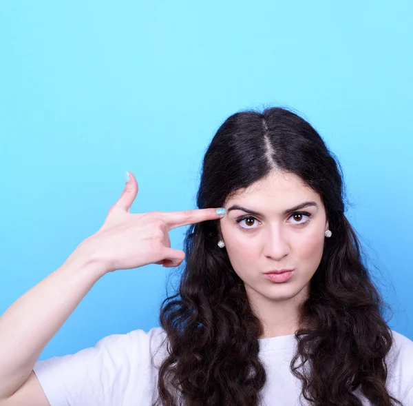 Retrato de chica enojada apuntando pistola hecha a mano contra ba azul —  Fotos de Stock