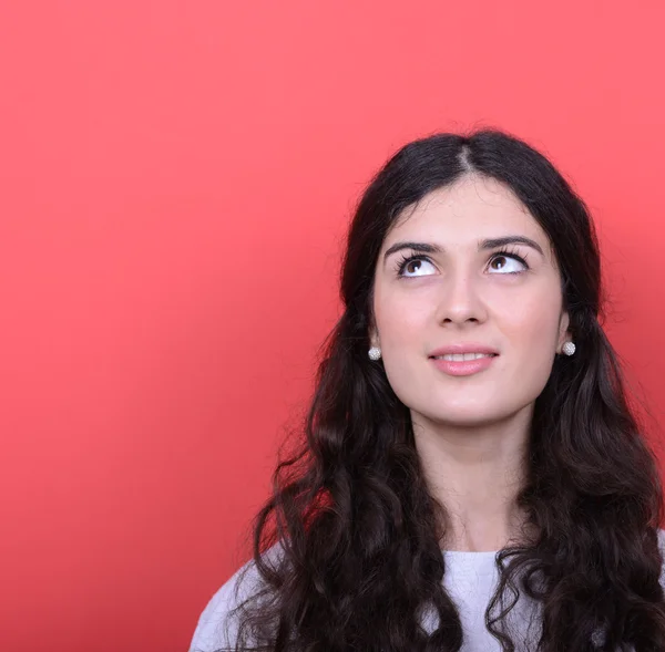 Portrait of beautiful girl looking up against red background — Stock Photo, Image