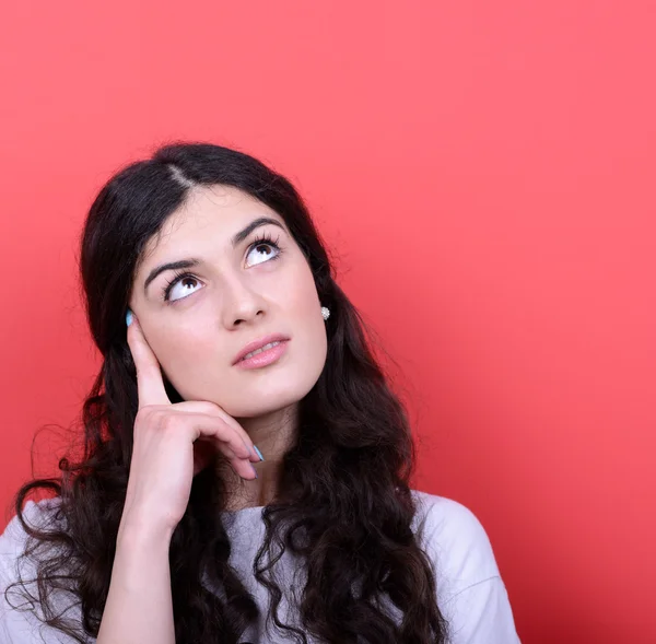 Retrato de menina bonita pensando e olhando para cima contra b vermelho — Fotografia de Stock