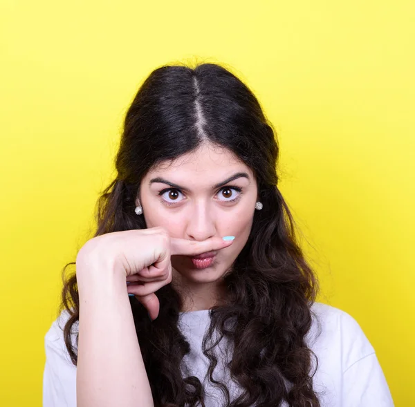 Portrait of funny girl making moustache against yellow backgroun — Stock Photo, Image