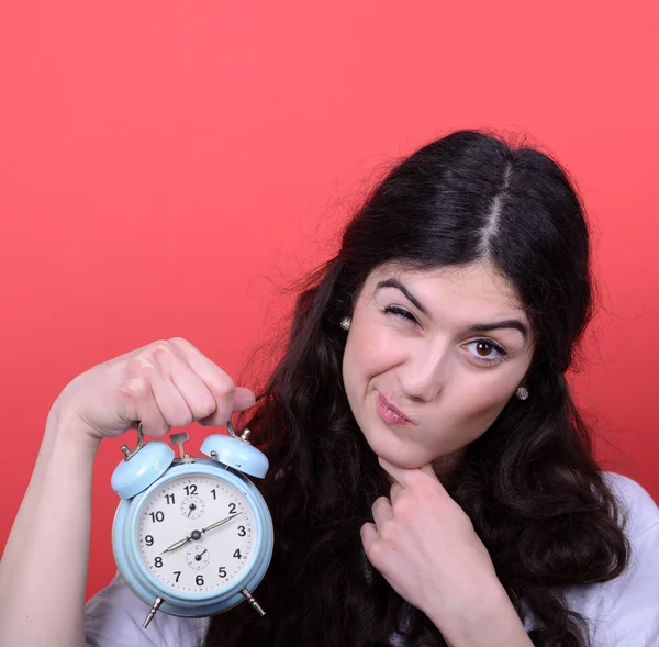 Porträt eines Mädchens, das auf Uhr vor rotem Hintergrund zeigt — Stockfoto