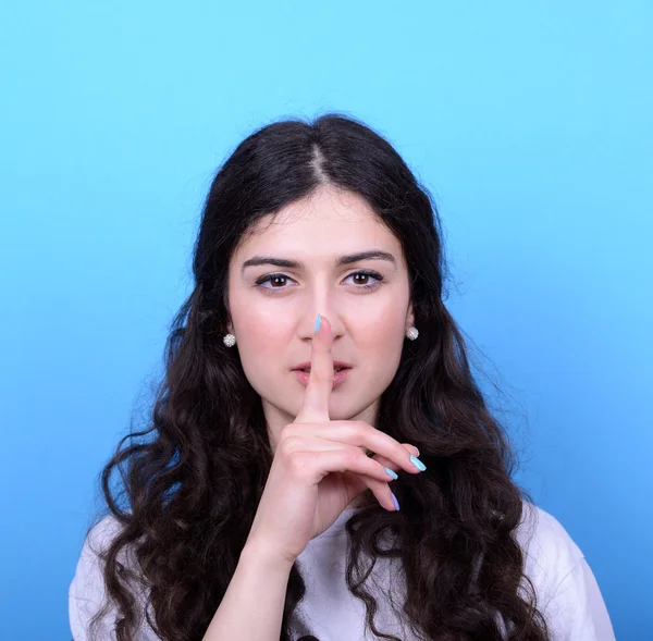 Retrato de menina com gesto de silêncio contra backgroun azul — Fotografia de Stock