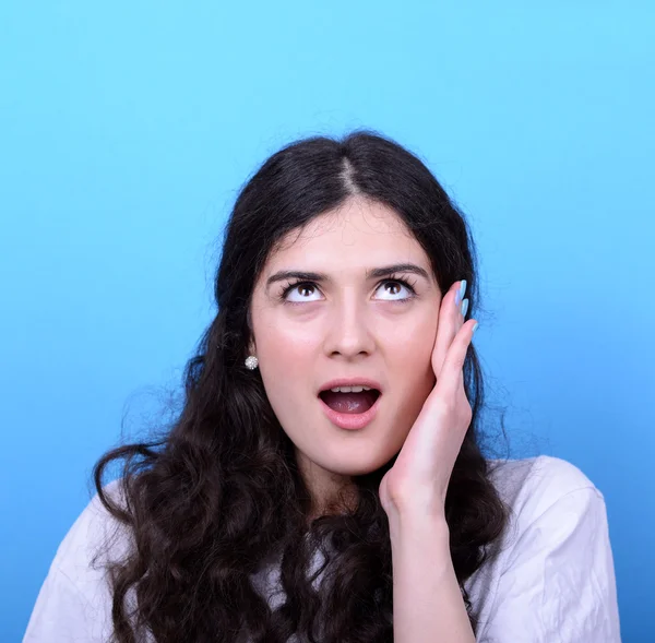 Portrait of girl with shock gesture looking up against blue back — Stock Photo, Image