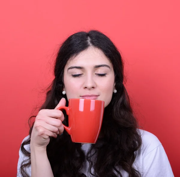 Porträtt av glad kvinna njuter av kopp kaffe mot röda backg — Stockfoto