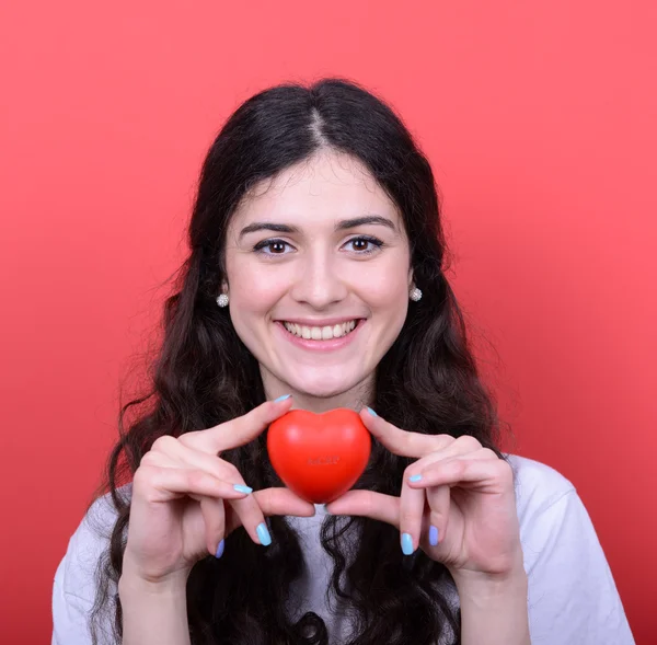 Retrato de mujer feliz sosteniendo el corazón en las manos contra el respaldo rojo — Foto de Stock