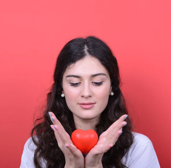 Retrato de mujer feliz sosteniendo el corazón en las manos contra el respaldo rojo — Foto de Stock