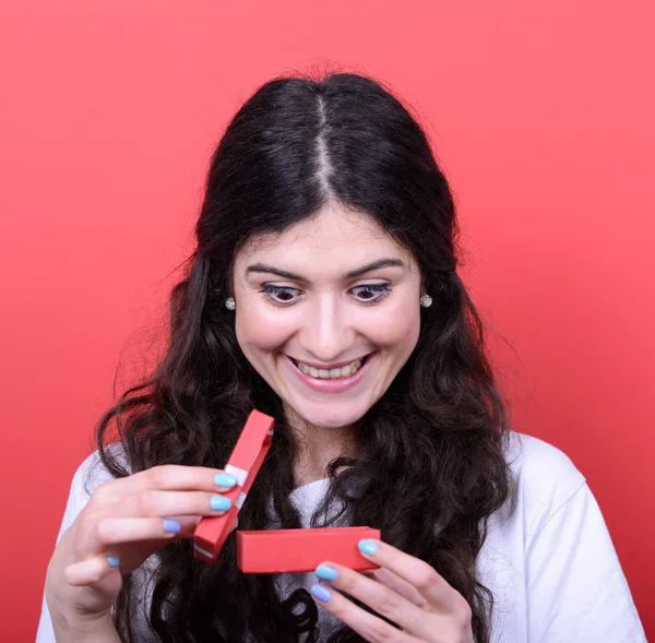 Portrait of happy woman opening gift box against red background — Stock Photo, Image