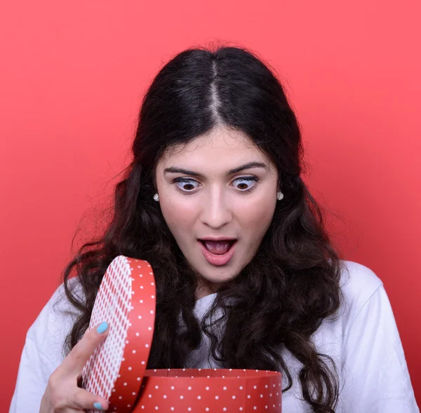 Retrato de mujer feliz abriendo caja de regalo sobre fondo rojo — Foto de Stock